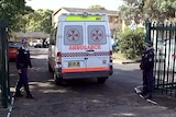 Police stand outside the Merrylands High School in Sydney as an ambulance enters