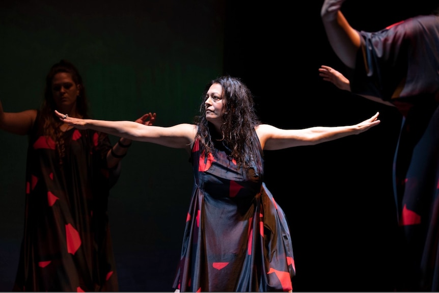 A woman with long brown hair extends her arms