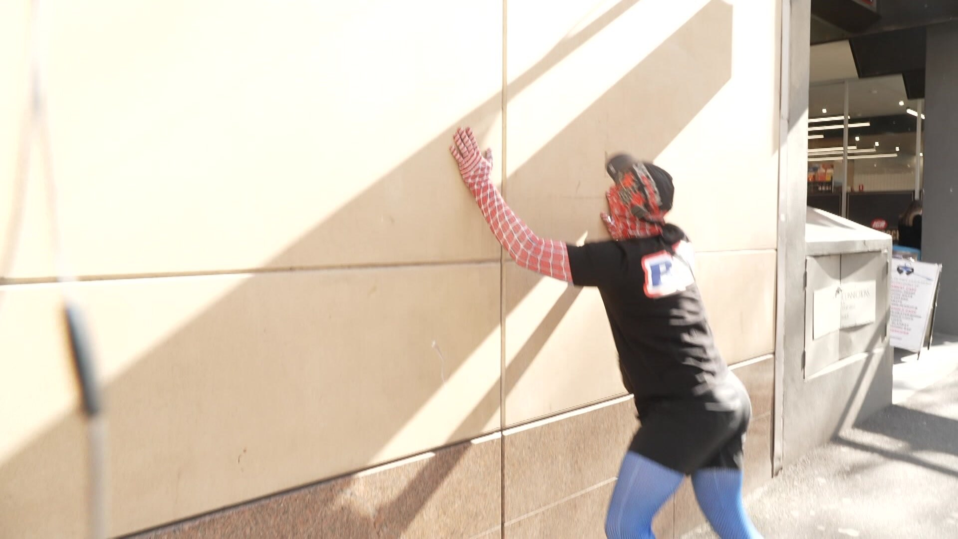 Jack Gibson-Burrell tries to scale a wall outside the court, dressed in a Spiderman costume.