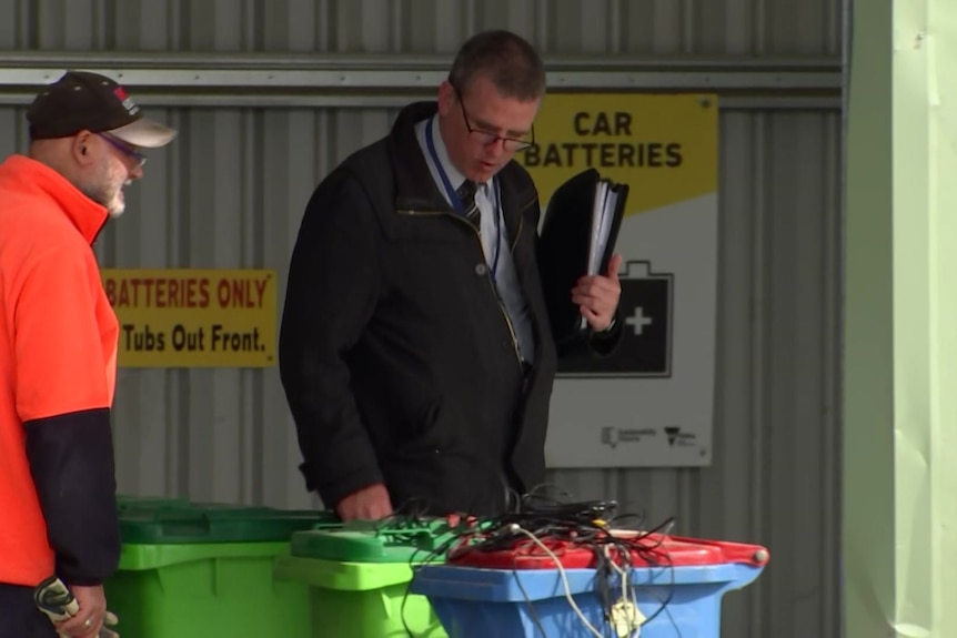 A police officer inspects plastic bins at Koonwarra tip near Leongatha.