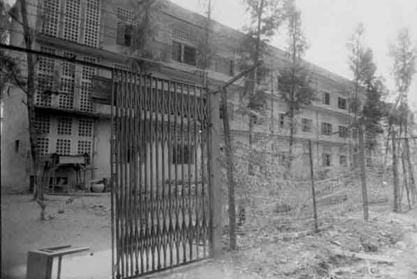 Czarno-białe zdjęcie zewnętrzne więzienia S-21 w Phnom Penh w 1979 roku.