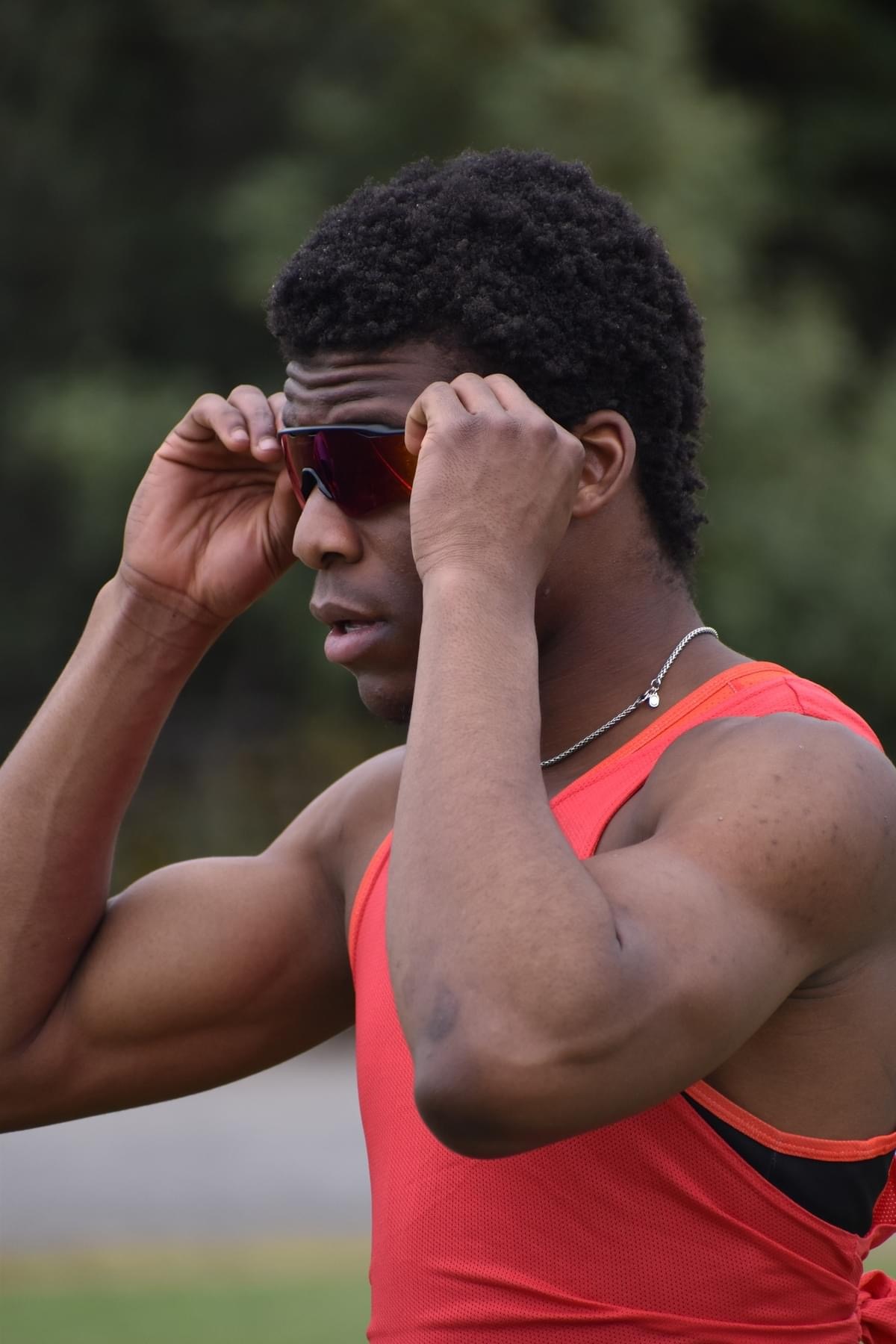 Um homem de camiseta vermelha coloca óculos escuros