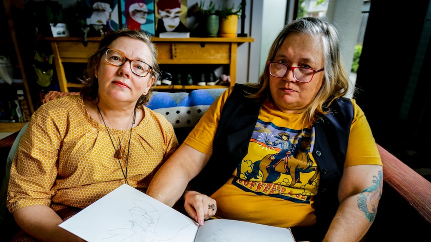 Clare Goss and Anthea Parsons sit beside one another inside.