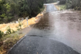 Water gushes over a country road