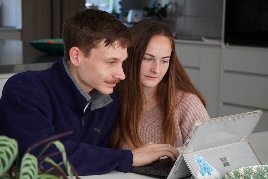 A close-up photograph of a young couple looking at a computer.