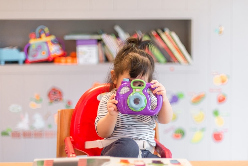 Little girl looking through a colourful toy camera