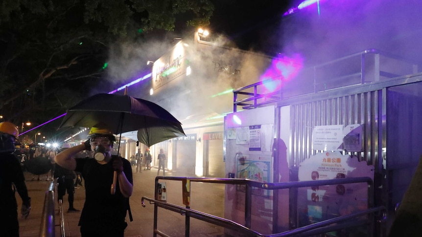 Protesters react to tear gas fired near the Tsim Sha Tsui police station in Hong Kong on Saturday.