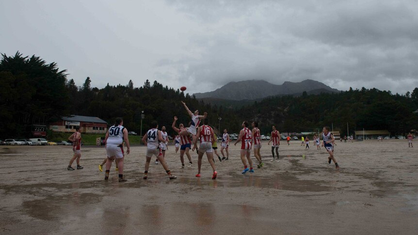 Picture of people playing football on a gravel oval