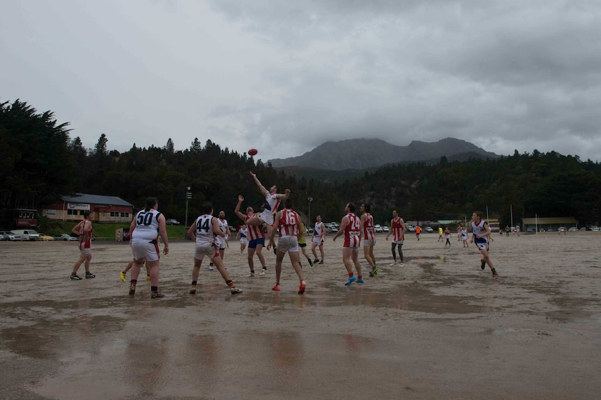 Picture of people playing football on a gravel oval