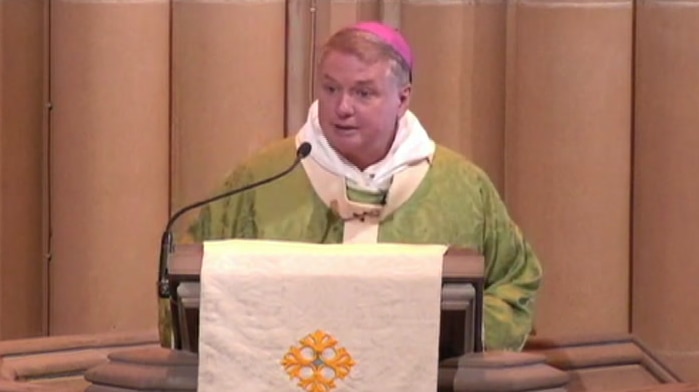 man at podium in catholic garbs