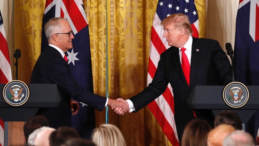Malcolm Turnbull and Donald Trump shake hands while standing behind US podiums