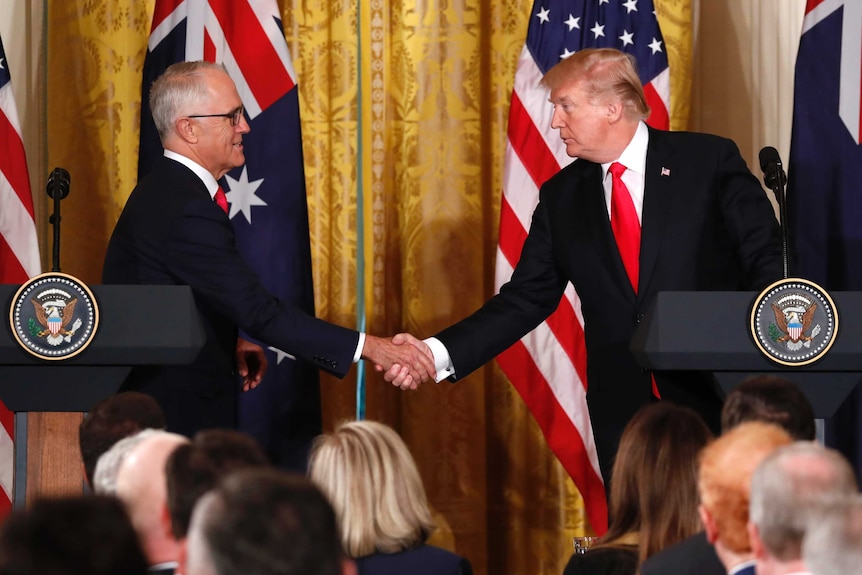 Malcolm Turnbull and Donald Trump shake hands while standing behind US podiums