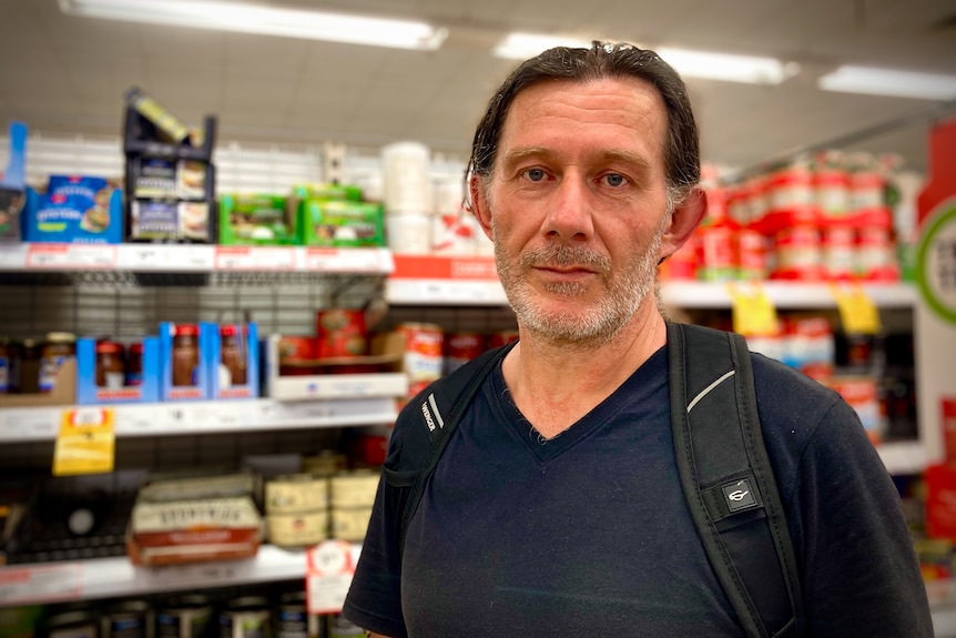 A middle-aged man with long hair standing in a supermarket