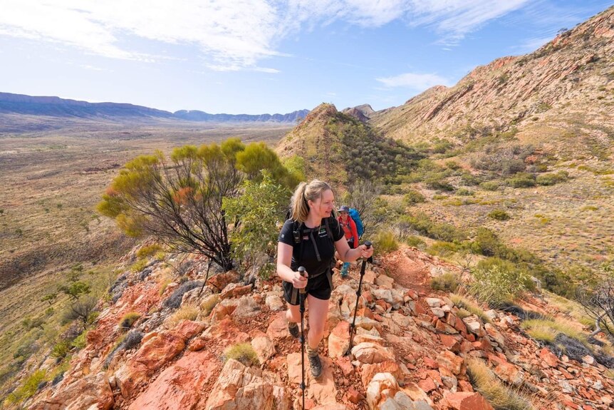 A woman walks up a rocky path in the outback.