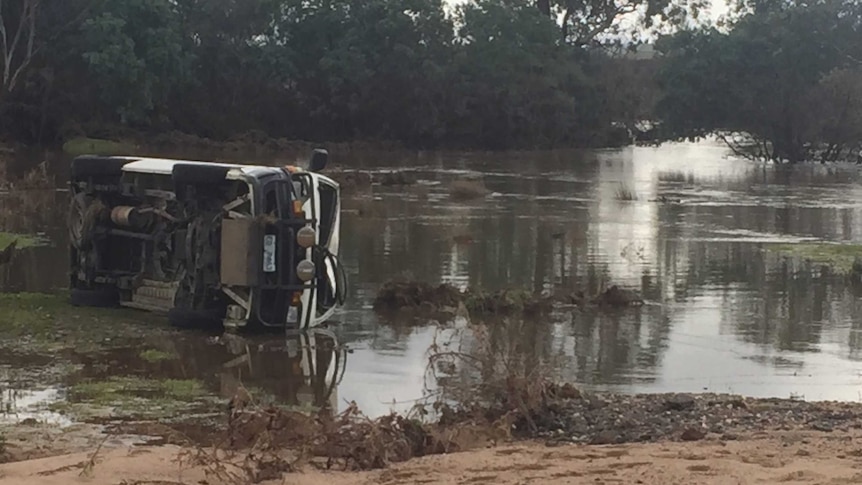 Van on its side on side of river.