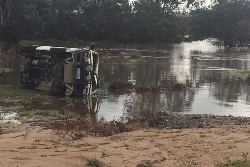 Van on its side on side of river.