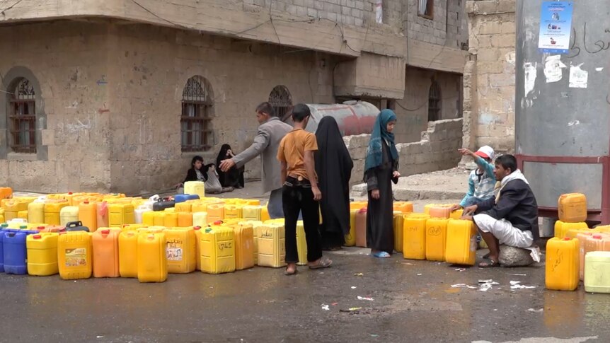 People queue on the street for water