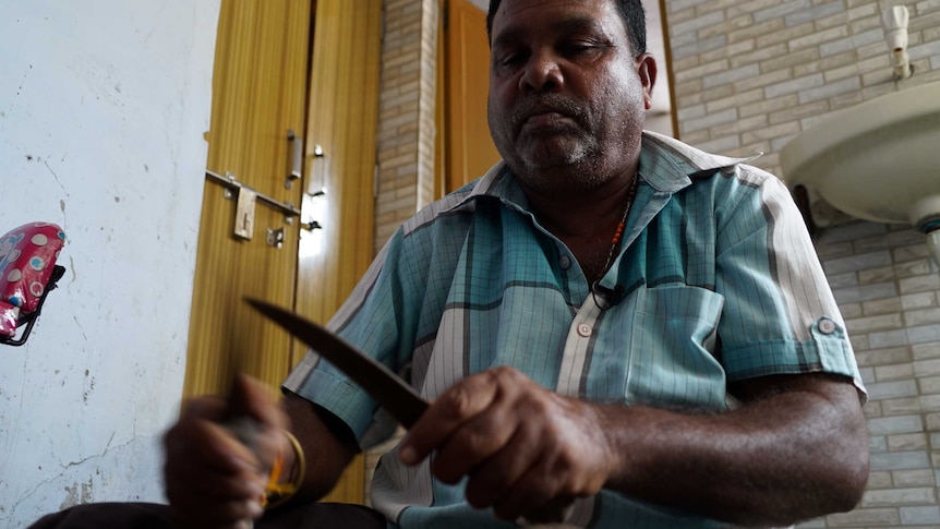 Dalit man, Somu Bhay Solanki, holding the knives he once used skin cattle.