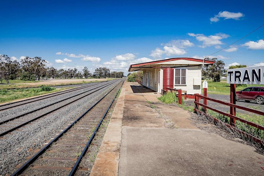 Railway lines on the left and small railway station and red car on the right