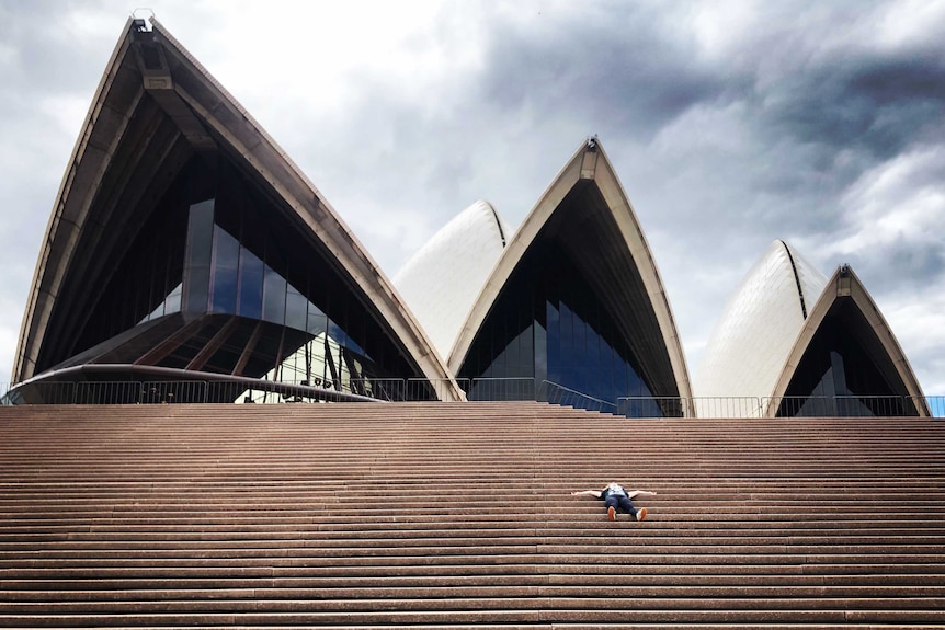 Georgia Mooney lying on the steps of the Opera House on her first day out of isolation