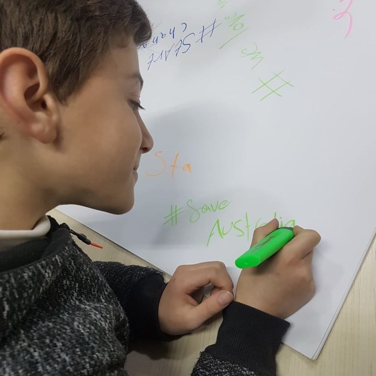 A picture of Anas Tahleh writing 'save Australia' on the group drawing.