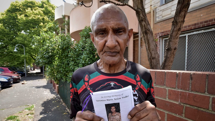 a man holds up a pamphlet with a photo of a woman on it