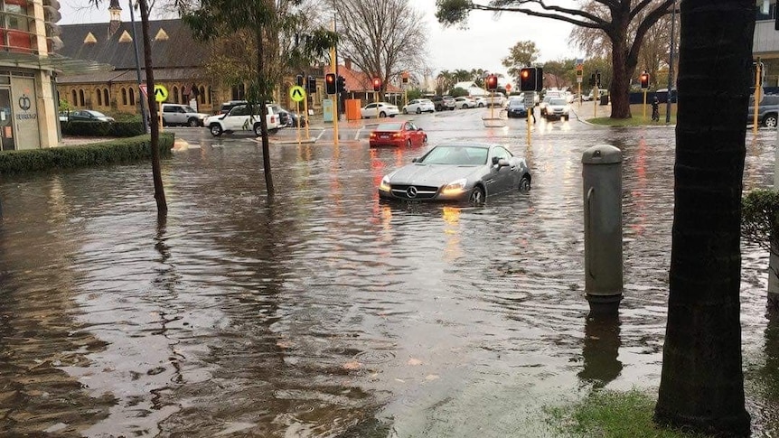 A photo of a car half submerged in water on a road in Claremont, in Perth.