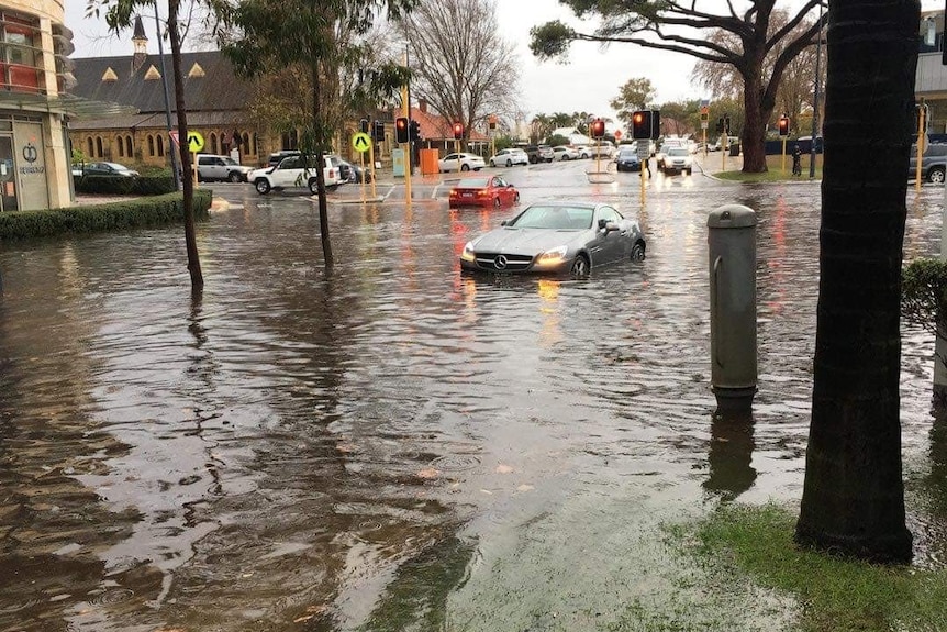 A photo of a car half submerged in water on a road in Claremont, in Perth.