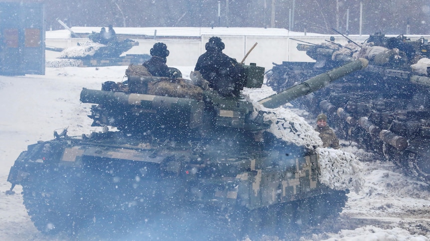 Ukrainian tanks drive during an exercise in the snow