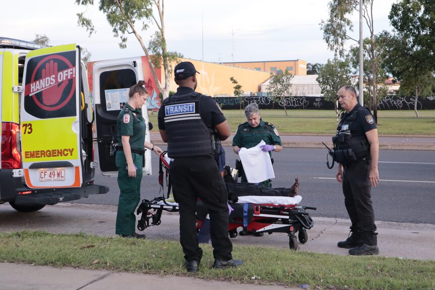 two female paramedics and two male police officers load a patient into an ambulance