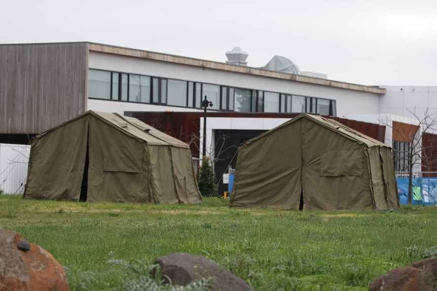 Two dark green tents are erected on a lawn outside the Epping Gardens aged care home buildings.