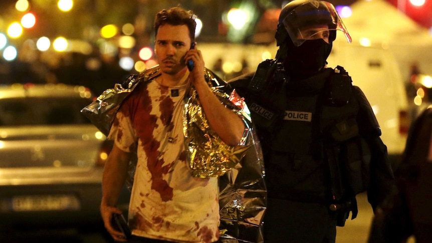 A member of the police assists a blood-covered victim