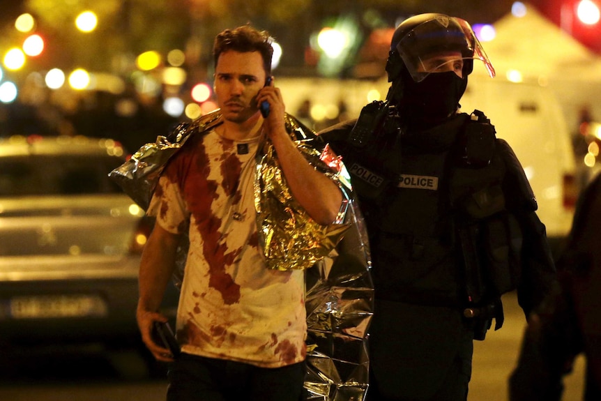 A member of the police assists a blood-covered victim