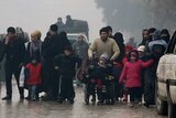 A group of civilians, including women and children, walk down run-down streets of Aleppo.
