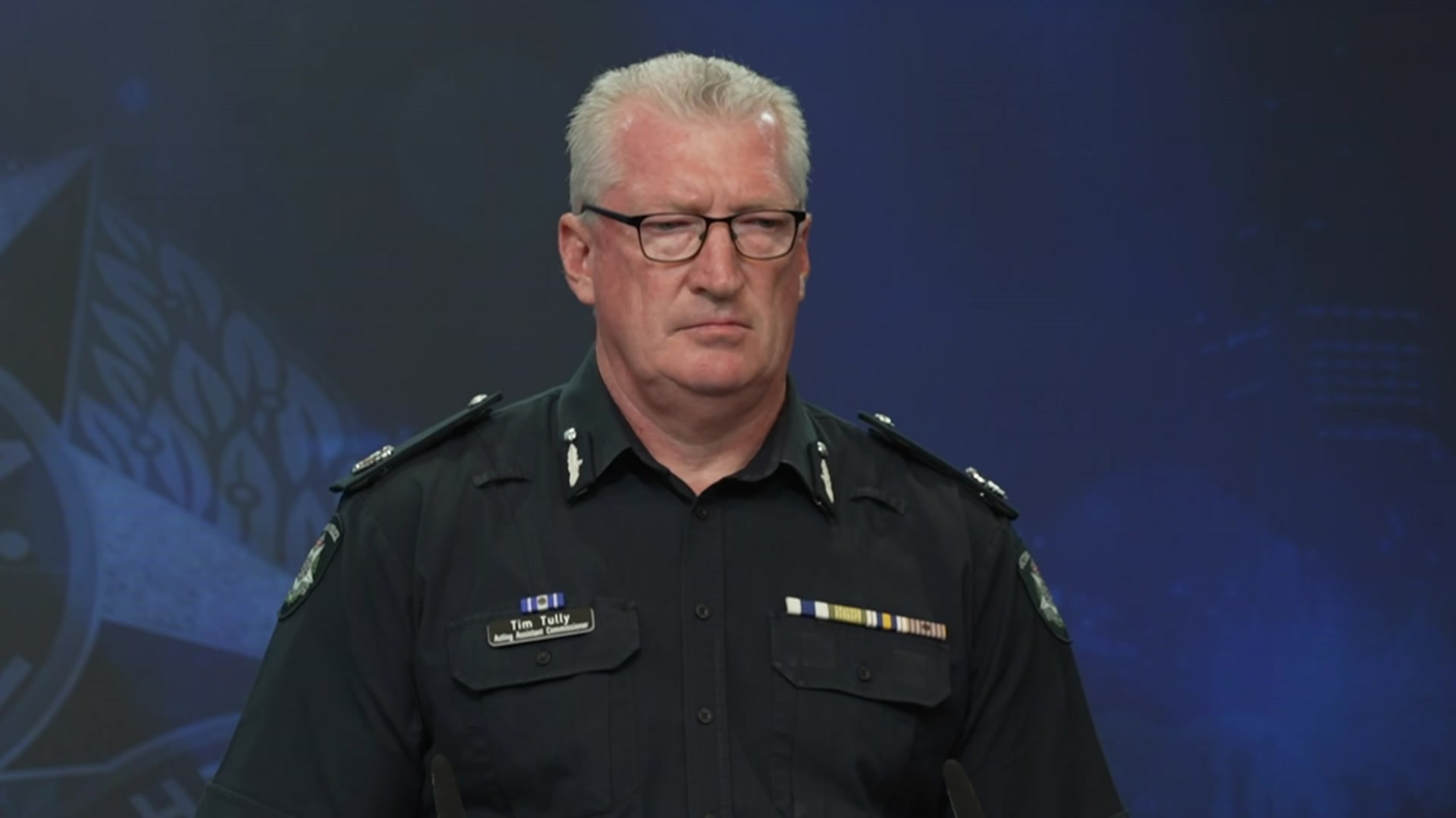 Tim Tully looks seriously at someone off camera.