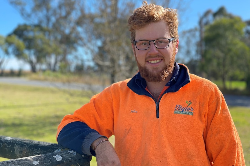 A man wearing a high-vis orange jumper stamding outdoors.