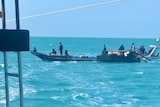 An illegal fishing boat, with an Australian Border Force boat in the background