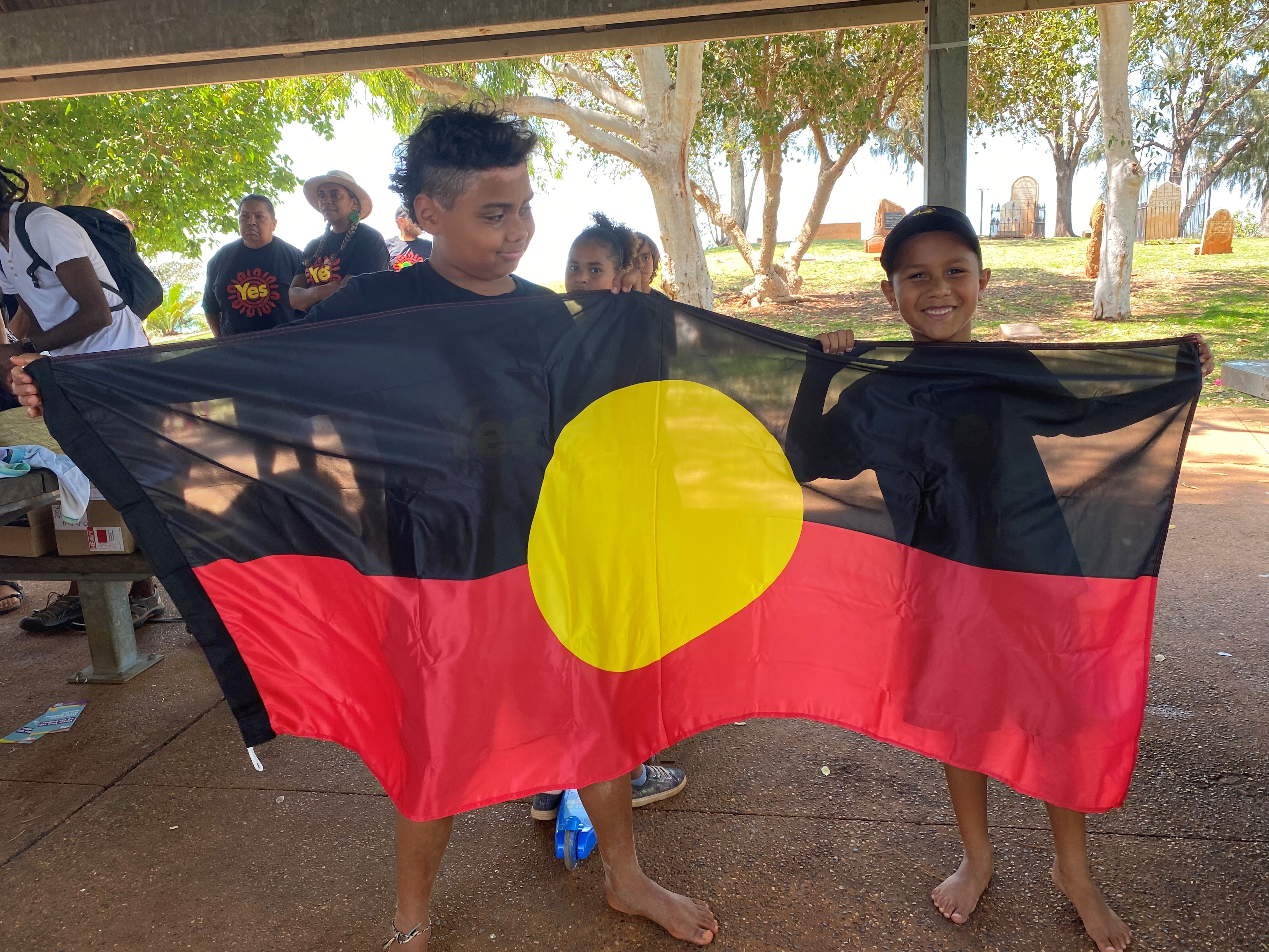 Two young indigenous boys told an Aboriginal flag. 