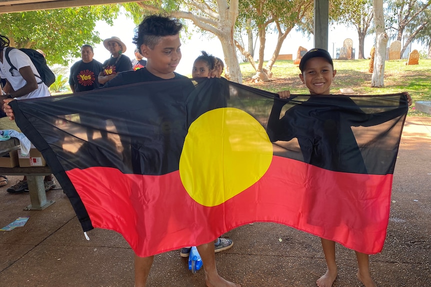 Two young indigenous boys told an Aboriginal flag. 