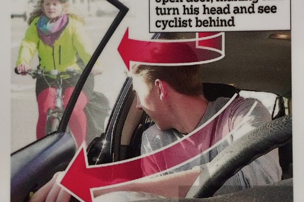 An image of a male driver reaching with his far hand and turning his head to see a cyclist behind him, with arrows and text