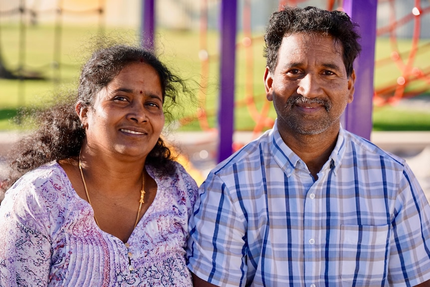 A couple of Tamil nationality smiling with colourful play equipment in the background