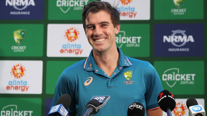 Pat Cummins smiles widely while speaking at a press conference