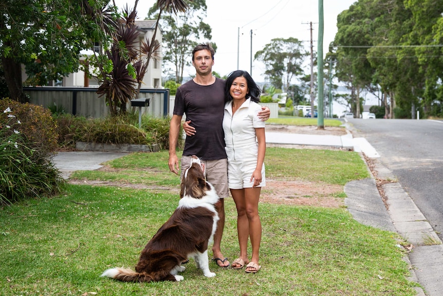 Jason Cullen and Tansiri Harnwattanachai stand out the front of their house with their dog at their feet.