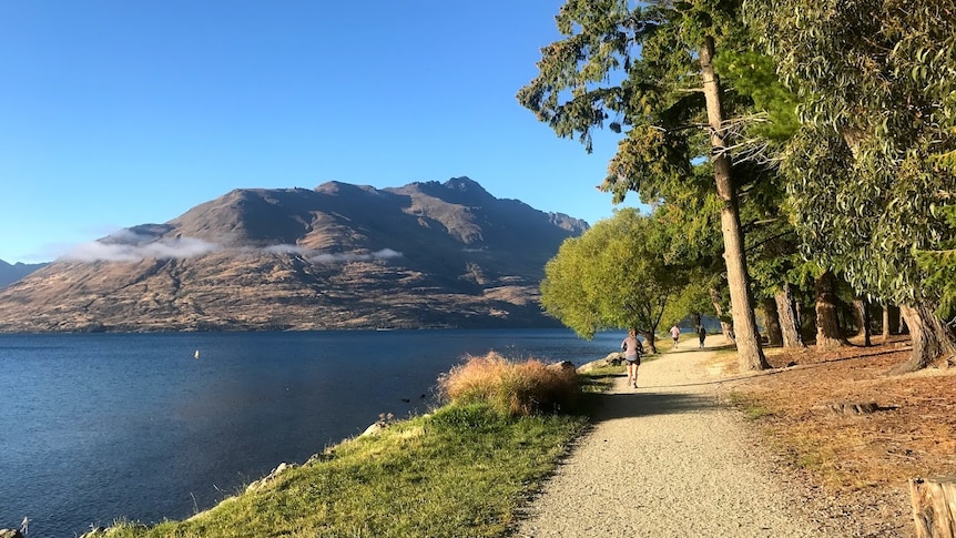 A running track by a lake goes off into the distance with a mountain in the background