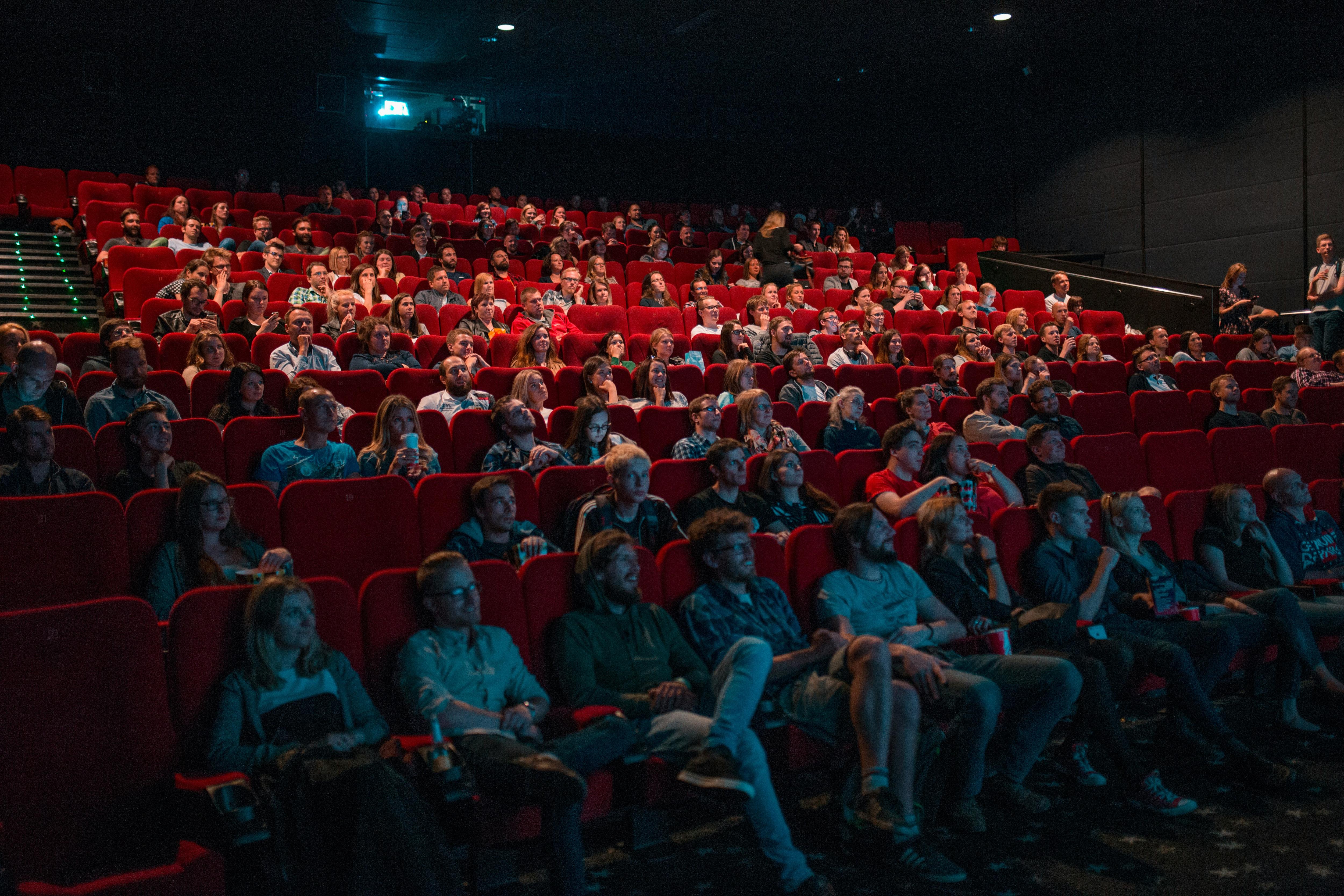 Docenas de personas dentro de una sala de cine viendo una película.
