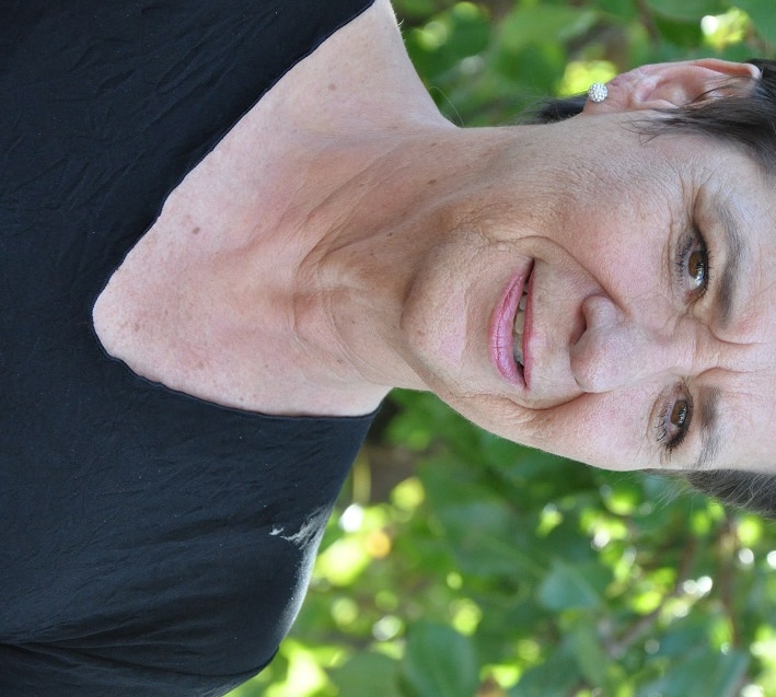 Woman stands in front of green foliage