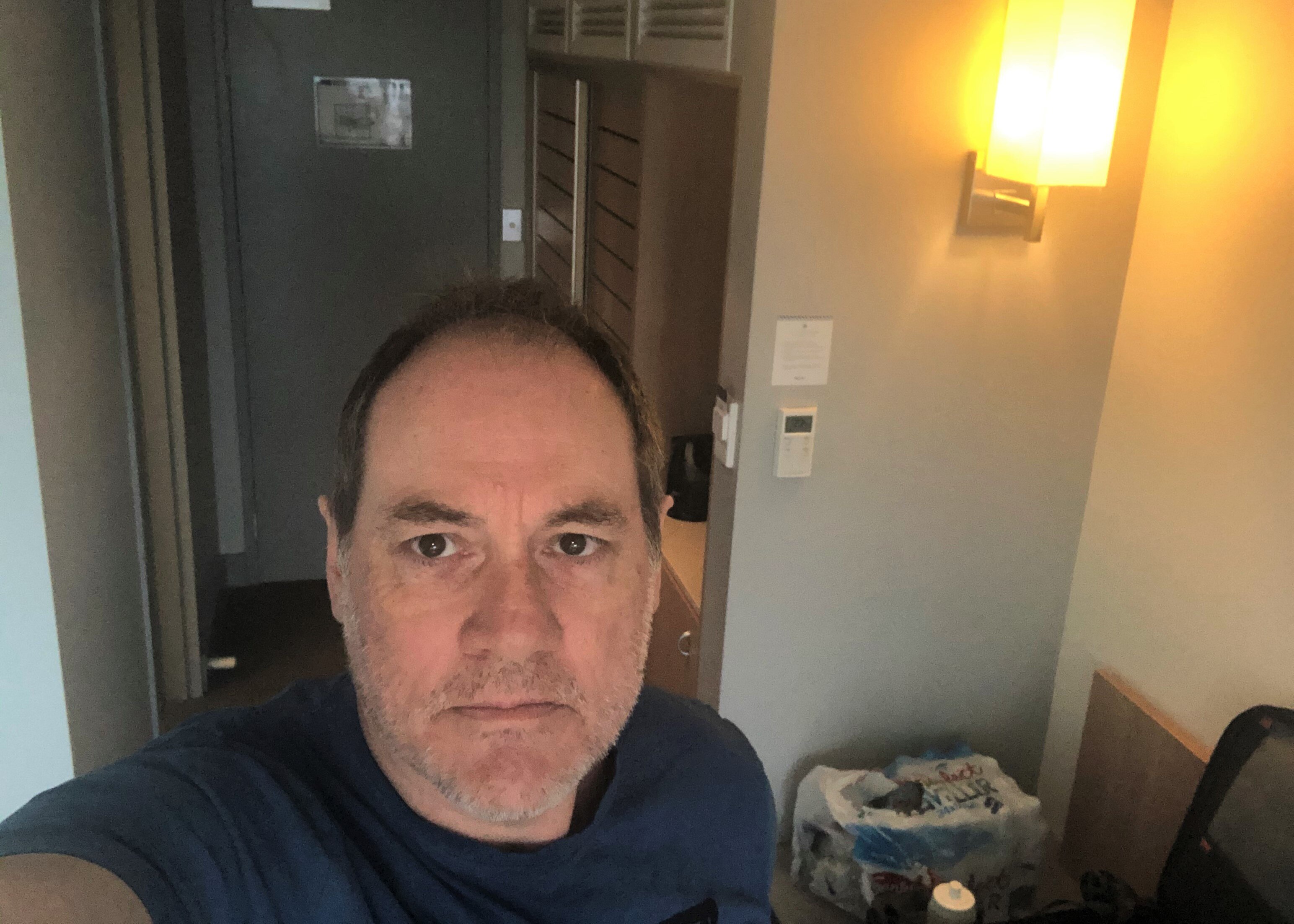 A head and shoulder shot of a man in a hotel room.
