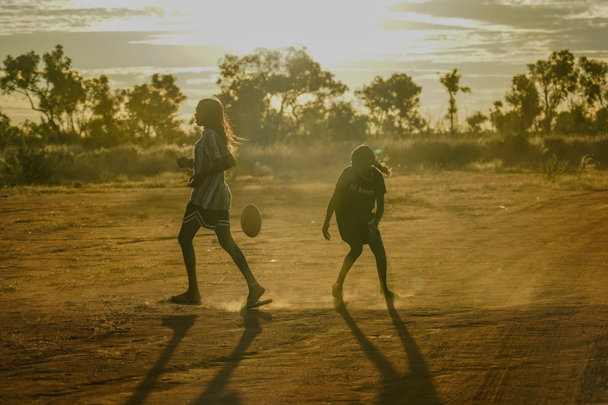 Girls playing football at sunset