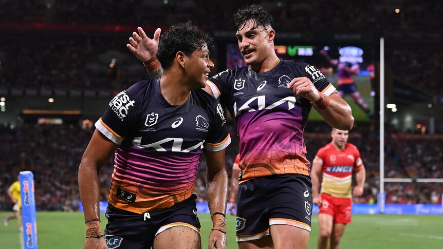 Two Brisbane Broncos NRL players celebrate a try against the Dolphins.