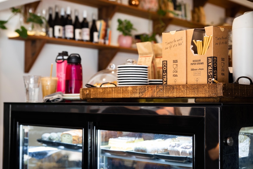 A box of paper straws sitting on the counter of a cafe.